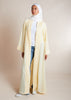 This open pleat abaya in buttercream boasts exquisite neat pleating that cascades down the placket and cuffs, offering a loose yet structured fit for all body types. Perfect as a quick cover-up for everyday outfits, or paired with one of our full slips for a more elegant ensemble. 
