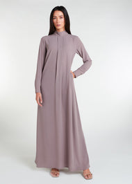 This Box Pleat Abaya Taupe features a fluid, A-line cut with a neat box pleat that runs from the high neck line to the bottom of the garment. The abaya is lightweight and airy, and a slip is necessary to wear underneath. 