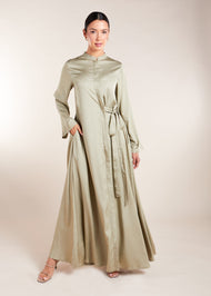 Discover the elegant and versatile Side Tie Abaya in an exquisite soft sage colour, crafted from a luxurious cotton satin blend that provides a subtle sheen. This abaya features a unique attached side belt that adds shape and dimension to the garment. 