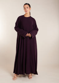 This elegant Two Piece Open Abaya set includes a Full Sleeve matching inner dress. Perfect for everyday wear, it can also be dressed up with accessories for an evening look. The open abaya can be worn as a maxi on its own or paired with the inner dress for a stylish ensemble. In a deep plum purple shade.